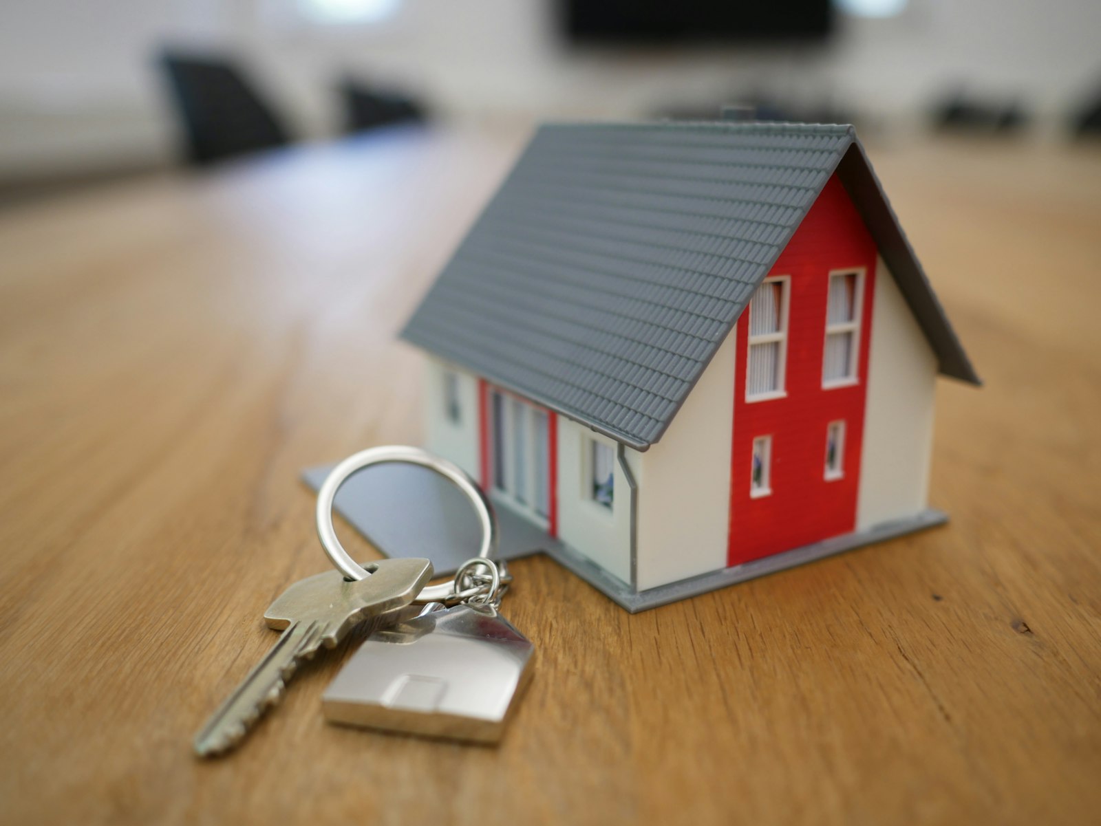 A small model house and a set of house keys on a wooden table