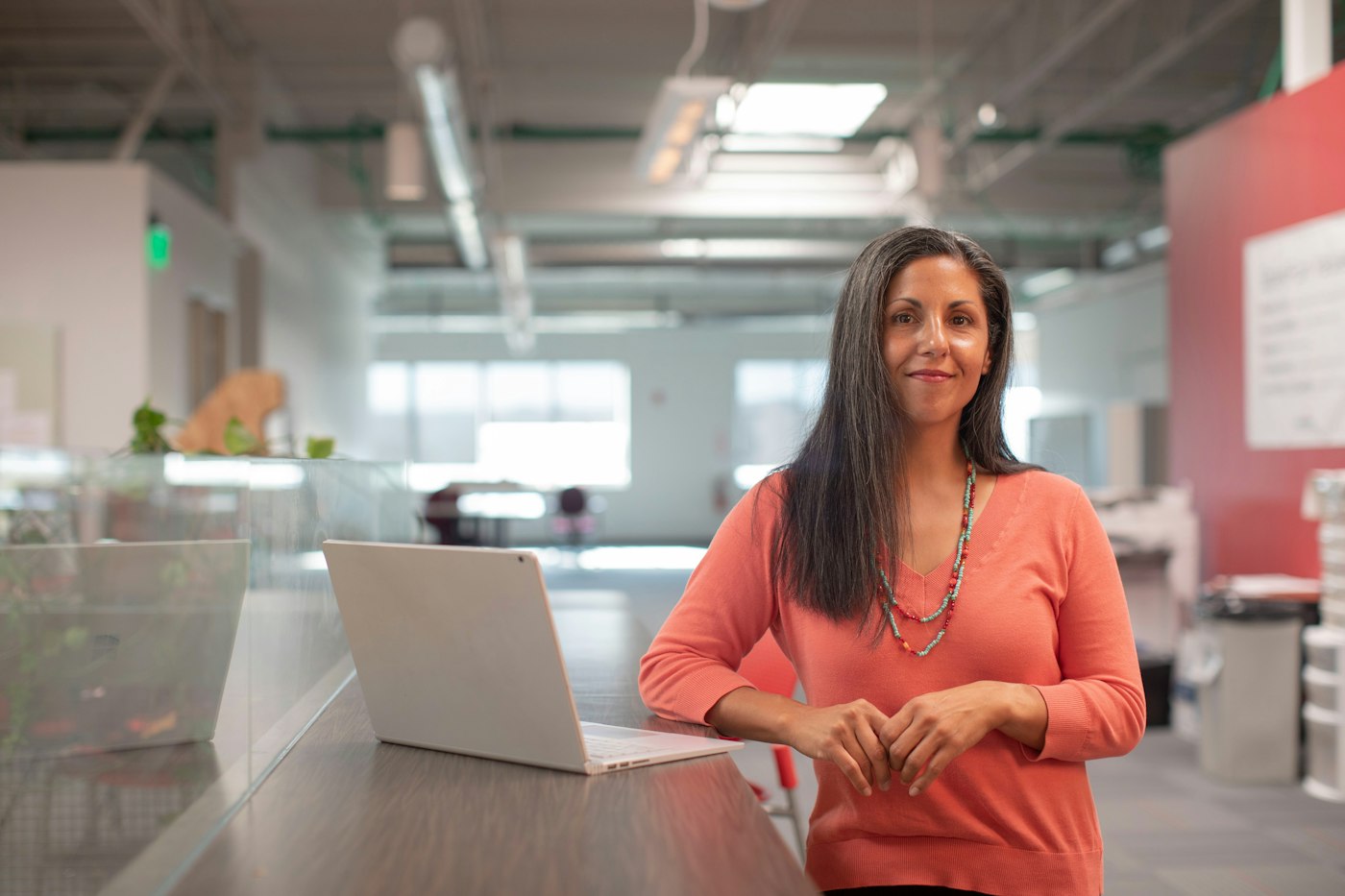 Business owner standing at her desk in an open-plan office